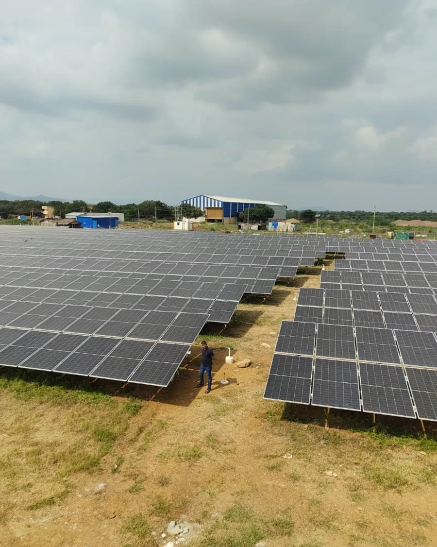 Ground-mount solar array on open land, an engineer standing between the rows