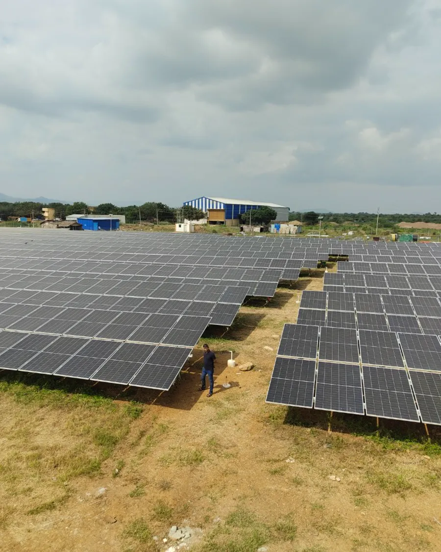 Ground-mount solar array on open land, an engineer standing between the rows