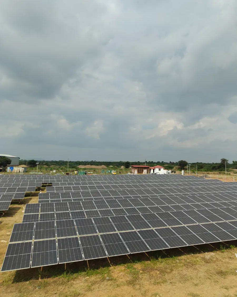 A ground-mount solar park with its control room visible behind the panel field